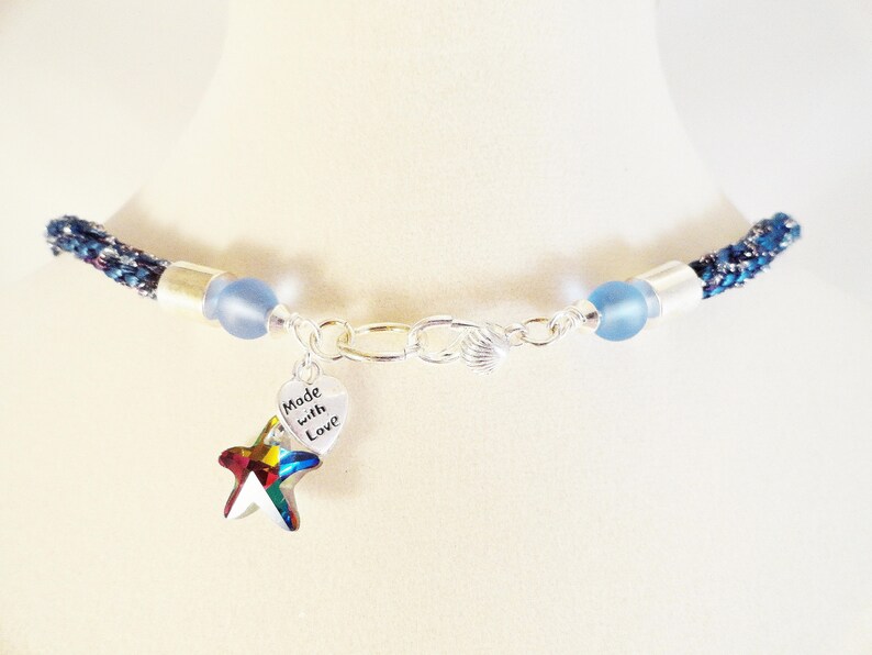May include: A blue and silver necklace with a charm that says "Made with Love" and a rainbow-colored starfish.