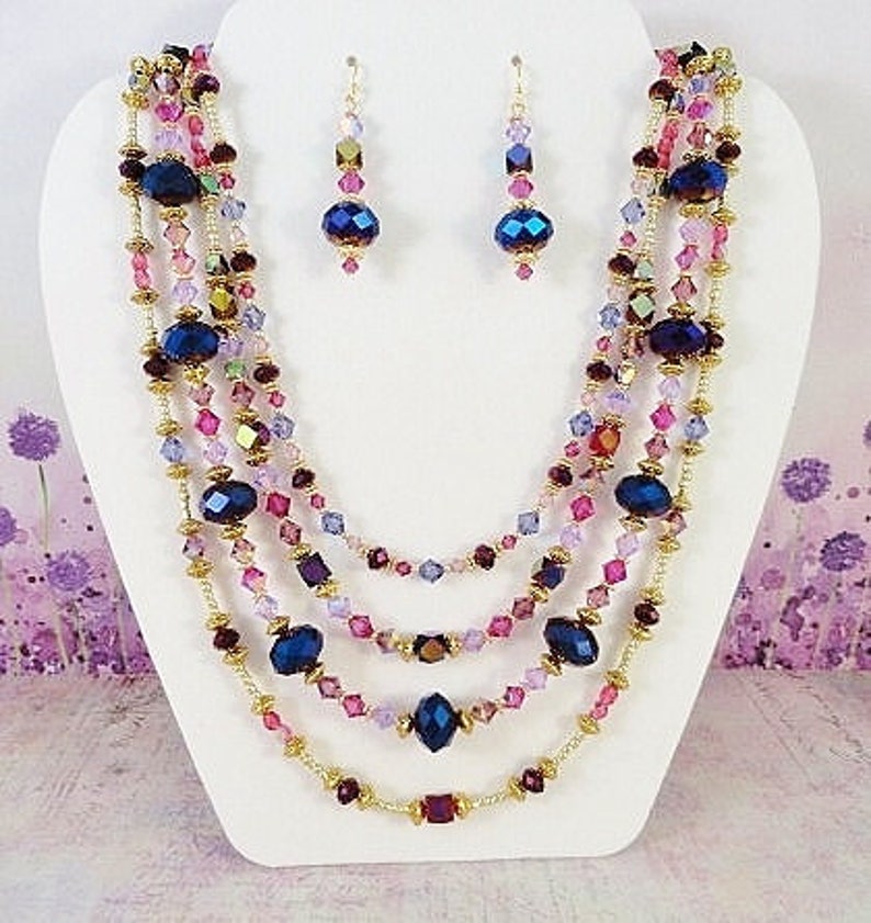 May include: Multi-strand necklace with pink, purple and blue crystal beads and gold accents. Matching earrings with blue crystal beads and gold accents.