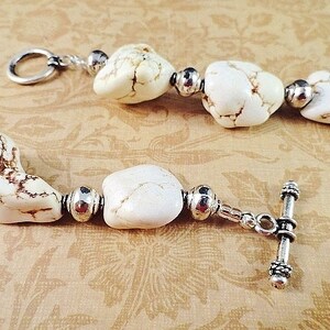 May include: A white howlite gemstone bracelet with silver tone beads and a toggle clasp.