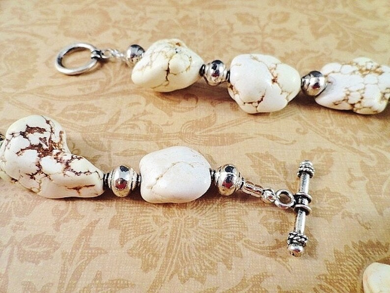 May include: A white howlite gemstone bracelet with silver tone beads and a toggle clasp.
