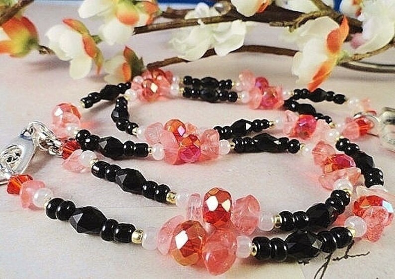 May include: A multi-strand necklace with black beads, pink and red faceted beads, and silver clasp.