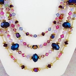 May include: Multi-strand necklace with gold chain and purple, pink, and blue crystal beads.