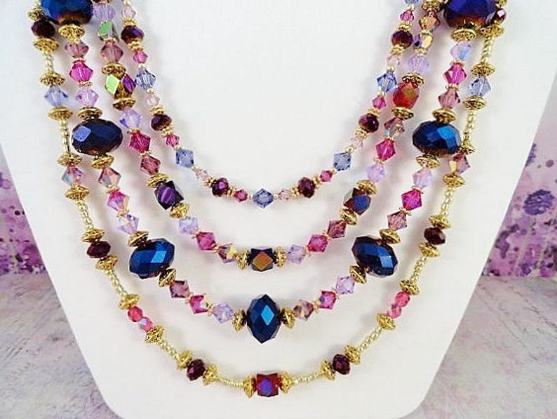 May include: Multi-strand necklace with gold chain and purple, pink, and blue crystal beads.