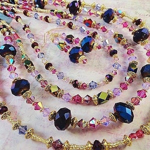 May include: Multi-strand necklace with gold accents and dark purple and pink crystal beads.