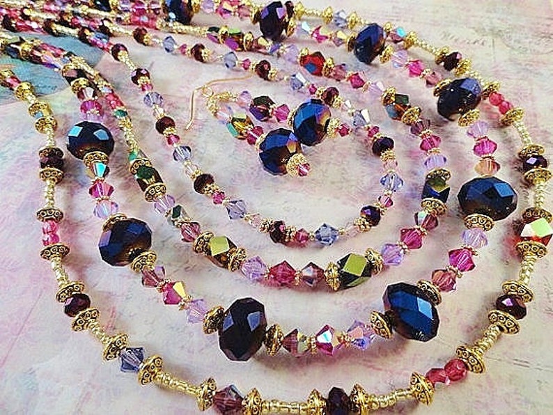 May include: Multi-strand necklace with gold accents and dark purple and pink crystal beads.