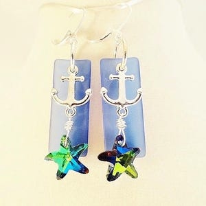 May include: A pair of silver anchor earrings with blue glass and green star-shaped crystals.