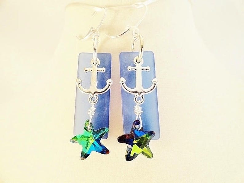 May include: A pair of silver anchor earrings with blue glass and green star-shaped crystals.