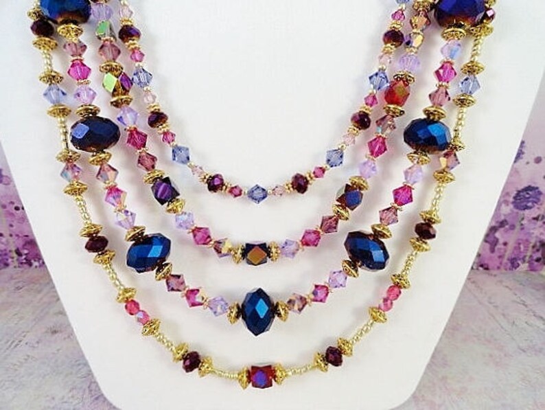 May include: Multi-strand necklace with gold chain and purple, pink, and blue crystal beads.