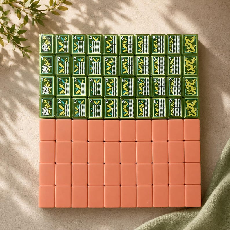 May include: A set of rectangular mahjong tiles arranged in a grid. The top four rows feature green tiles with white, yellow, and black illustrations of bamboo, numbers one through nine, and dragon motifs. The bottom four rows consist of solid peach tiles.