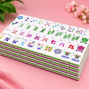 K&ouml;nnte beinhalten: Ein Set wei&szlig;er Mahjong-Spielsteine, angeordnet in einem rechteckigen Raster. Die Steine zeigen farbenfrohe, eingravierte Motive wie Zahlen, Bambusstangen, chinesische Schriftzeichen, Blumenmuster, die Buchstaben N, W, S sowie zwei JOKER-Steine.