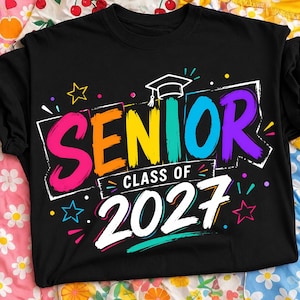 May include: A black t-shirt featuring a colorful graphic with the text SENIOR CLASS OF 2027. The word SENIOR is in large, multi-colored brushstroke letters, topped with a white graduation cap icon. The text 2027 is in large white letters.