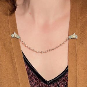 These vintage sweater clips are an absolute treasure. Featuring light gold butterfly clips connected to a cream pearl linked chain. These whimsical butterflies have small alligator clips that gently and securely clip to a cardigan/sweater/jacket/collar, for an instantly elevated look. Sweater clips are a classic vintage accessory popular in the 1940s and 1950s.