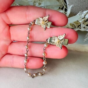 These vintage sweater clips are an absolute treasure. Featuring light gold butterfly clips connected to a cream pearl linked chain. These whimsical butterflies have small alligator clips that gently and securely clip to a cardigan/sweater/jacket/collar, for an instantly elevated look. Sweater clips are a classic vintage accessory popular in the 1940s and 1950s.