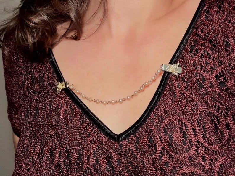 These vintage sweater clips are an absolute treasure. Featuring light gold butterfly clips connected to a cream pearl linked chain. These whimsical butterflies have small alligator clips that gently and securely clip to a cardigan/sweater/jacket/collar, for an instantly elevated look. Sweater clips are a classic vintage accessory popular in the 1940s and 1950s.