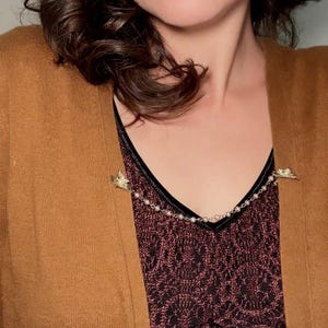These vintage sweater clips are an absolute treasure. Featuring light gold butterfly clips connected to a cream pearl linked chain. These whimsical butterflies have small alligator clips that gently and securely clip to a cardigan/sweater/jacket/collar, for an instantly elevated look. Sweater clips are a classic vintage accessory popular in the 1940s and 1950s.