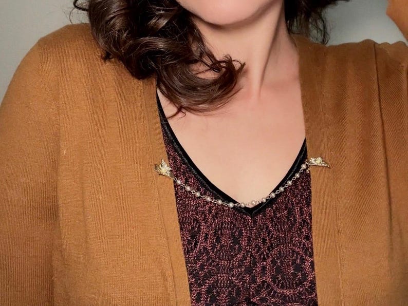These vintage sweater clips are an absolute treasure. Featuring light gold butterfly clips connected to a cream pearl linked chain. These whimsical butterflies have small alligator clips that gently and securely clip to a cardigan/sweater/jacket/collar, for an instantly elevated look. Sweater clips are a classic vintage accessory popular in the 1940s and 1950s.