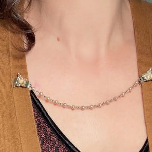 These vintage sweater clips are an absolute treasure. Featuring light gold butterfly clips connected to a cream pearl linked chain. These whimsical butterflies have small alligator clips that gently and securely clip to a cardigan/sweater/jacket/collar, for an instantly elevated look. Sweater clips are a classic vintage accessory popular in the 1940s and 1950s.