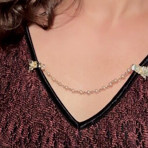 These vintage sweater clips are an absolute treasure. Featuring light gold butterfly clips connected to a cream pearl linked chain. These whimsical butterflies have small alligator clips that gently and securely clip to a cardigan/sweater/jacket/collar, for an instantly elevated look. Sweater clips are a classic vintage accessory popular in the 1940s and 1950s.