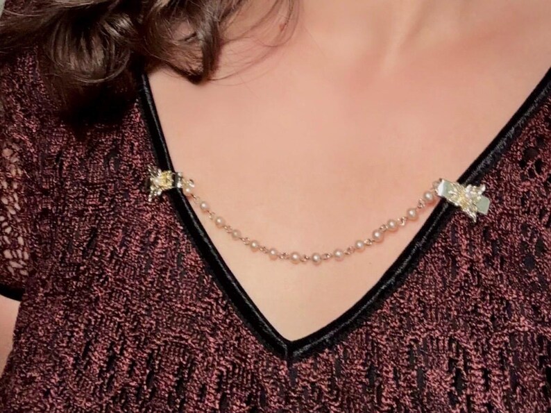 These vintage sweater clips are an absolute treasure. Featuring light gold butterfly clips connected to a cream pearl linked chain. These whimsical butterflies have small alligator clips that gently and securely clip to a cardigan/sweater/jacket/collar, for an instantly elevated look. Sweater clips are a classic vintage accessory popular in the 1940s and 1950s.