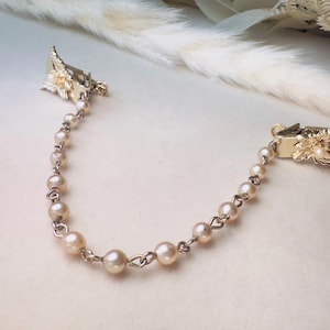 These vintage sweater clips are an absolute treasure. Featuring light gold butterfly clips connected to a cream pearl linked chain. These whimsical butterflies have small alligator clips that gently and securely clip to a cardigan/sweater/jacket/collar, for an instantly elevated look. Sweater clips are a classic vintage accessory popular in the 1940s and 1950s.