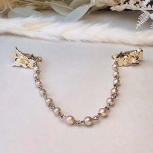 These vintage sweater clips are an absolute treasure. Featuring light gold butterfly clips connected to a cream pearl linked chain. These whimsical butterflies have small alligator clips that gently and securely clip to a cardigan/sweater/jacket/collar, for an instantly elevated look. Sweater clips are a classic vintage accessory popular in the 1940s and 1950s.