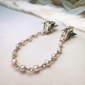 These vintage sweater clips are an absolute treasure. Featuring light gold butterfly clips connected to a cream pearl linked chain. These whimsical butterflies have small alligator clips that gently and securely clip to a cardigan/sweater/jacket/collar, for an instantly elevated look. Sweater clips are a classic vintage accessory popular in the 1940s and 1950s.