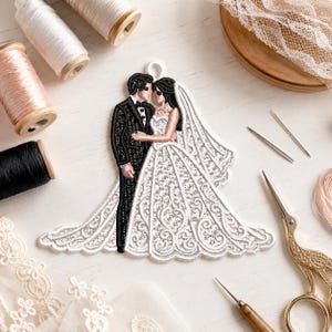 May include: An embroidered patch depicting a couple in wedding attire. The figure on the left wears a black suit, while the figure on the right wears a white gown with intricate lace-like patterns and a long veil. The patch has a small loop at the top.