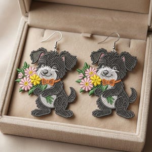 May include: A pair of dangle earrings featuring a black dog with a white chest and muzzle, wearing an orange bow tie and holding a bouquet of pink and yellow flowers. The dog design has a textured, embroidered appearance with silver-toned hooks.