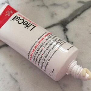 May include: A white and red squeeze tube of LifeCell All-In-One Anti-Aging Treatment skincare cream. The tube features black text listing benefits like anti-wrinkle and hydration, with a small amount of beige cream dispensed from the nozzle, 75 ml.