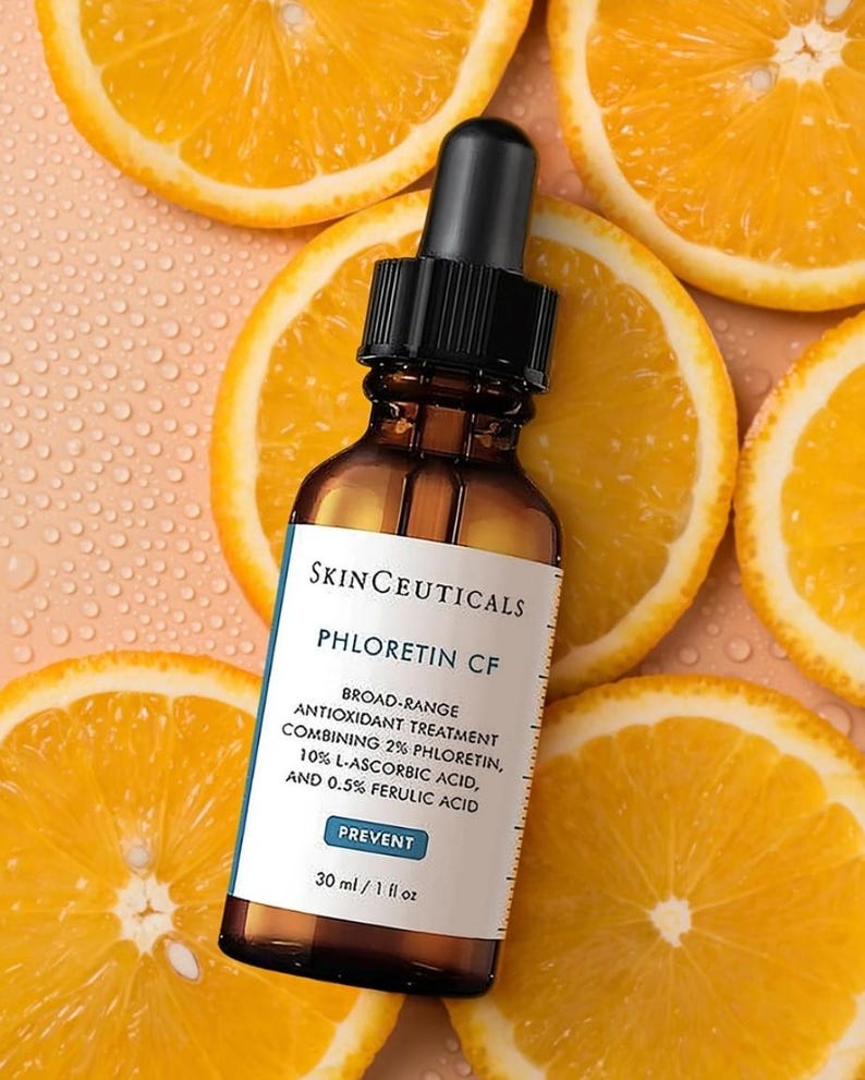 Op de afbeelding: Een bruine glazen druppelfles met SkinCeuticals Phloretin CF antioxidantbehandeling en een zwarte dop. Het etiket vermeldt 2% phloretine, 10% L-ascorbinezuur en 0,5% ferulazuur, met een inhoud van 30 ml / 1 fl oz.