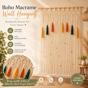Op de afbeelding: Een grote off-white macramé wandhanger opgehangen aan een houten stok, met ingewikkelde knooppatronen, lange franjes en afwisselende blauwgroene, oranje en gele kwastjes, geaccentueerd met kleine kleurrijke kralen verspreid over het ontwerp.