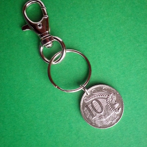 Puede incluir: Llavero de plata con un dije de moneda de plata que presenta el número 10 y un diseño de un canguro. El llavero tiene un cierre de langosta de plata.