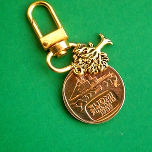 May include: Gold-colored keychain with a small tree charm and a round coin with the text "SUOMI FINLAND 1993".