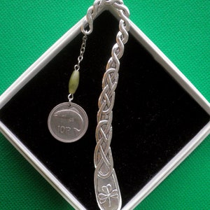 May include: Silver Celtic knot bookmark with a shamrock design at the bottom and a dangling green bead and a 10 pence coin with a fish design.