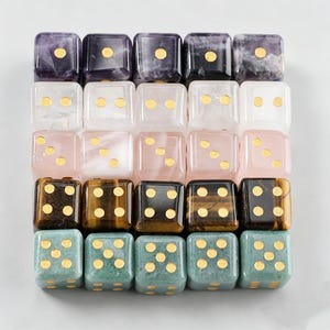 May include: A collection of twenty-five square dice arranged in a five-by-five grid. Each row features a different stone material, including purple amethyst, clear quartz, pink rose quartz, brown tiger's eye, and green aventurine with gold pips.