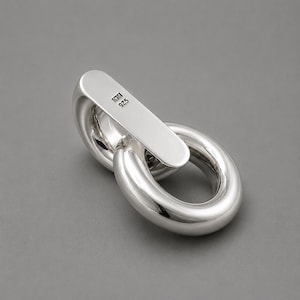 May include: A polished silver-tone metal link component featuring a smooth, rounded, oval-shaped loop connected to a flat, rectangular bar. The bar is stamped with the text KM and 925, indicating sterling silver composition and a maker mark.