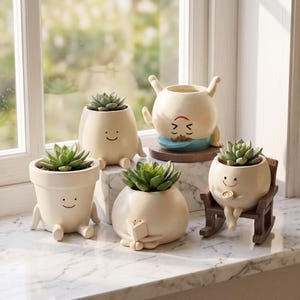 May include: Five cream-colored ceramic planters shaped like small characters, each holding a green succulent. One sits on a brown rocking chair, one reads a book, one does a handstand, and two sit upright. The planters feature simple painted faces.