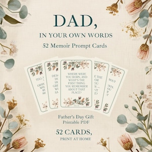 May include: A set of 52 memoir prompt cards titled DAD, IN YOUR OWN WORDS. The cards feature dark green text on a cream background with floral illustrations. The center card asks, WHERE WERE YOU BORN, AND WHAT'S THE FIRST THING YOU REMEMBER ABOUT THAT PLACE?