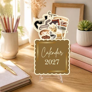 May include: A 2027 calendar featuring a brown scalloped-edge card with gold border lines and the text Calendar 2027. The top section displays illustrations of coffee beans, various coffee drinks, and a sugar bag on a clear stand.