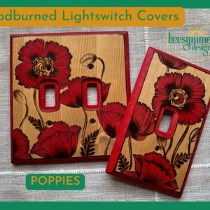 May include: Woodburned lightswitch covers with red poppy flower designs. The covers are made of light-colored wood with a red border. The word "POPIES" is in a green rectangle at the bottom. The text "Woodburned Lightswitch Covers" is at the top.
