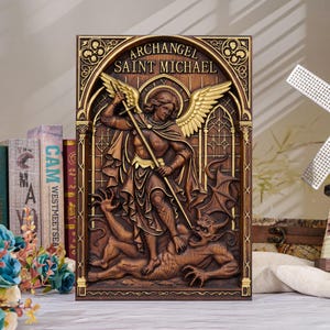 Puede incluir: Una placa de pared rectangular con un relieve del Arcángel San Miguel derrotando a un demonio. La pieza tiene un acabado en tonos marrón y dorado, con el texto "ARCHANGEL SAINT MICHAEL" inscrito en la parte superior dentro de un marco arqueado.