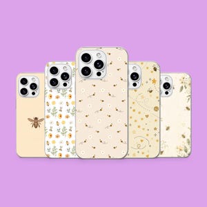 Puede incluir: Cinco fundas para smartphone dispuestas en fila, cada una con un diseño único en tonos crema y amarillo. Los patrones incluyen una abeja solitaria, motivos florales, pequeñas abejas con margaritas, estrellas, corazones y dibujos botánicos.