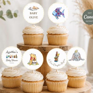 Puede incluir: Seis cupcakes con adornos circulares de papel que presentan ilustraciones de Winnie the Pooh, Dumbo, un pez colorido y un mono leyendo libros. El texto incluye Baby Olive, Agatha's Baby Shower y A New Chapter Begins.