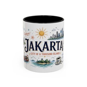 Könnte beinhalten: Ein weißer Keramikbecher mit schwarzem Innenraum, verziert mit einer farbenfrohen Illustration der Skyline von Jakarta, einer tropischen Insel, einem Boot und einer Kaffeetasse. Der Text lautet Jakarta, City of a Thousand Islands und Jaiakarta.