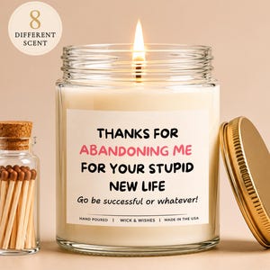 May include: A lit candle in a clear glass jar with a gold lid and a white label reading: THANKS FOR ABANDONING ME FOR YOUR STUPID NEW LIFE. Go be successful or whatever! HAND POURED | WICK & WISHES | MADE IN THE USA. Beside it is a small glass vial of matches.