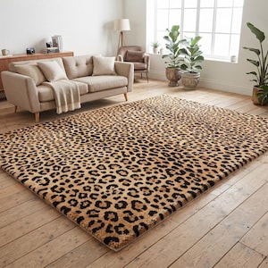 May include: A rectangular area rug featuring a repeating leopard print pattern in shades of tan, brown, and black. The rug is laid flat on a light-coloured wooden floor, covering a significant portion of the room's floor space.
