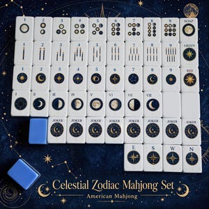 May include: A Celestial Zodiac Mahjong set featuring white tiles with blue and gold celestial illustrations. The set includes numbered tiles 1-9, moon phase tiles I-VIII, Joker tiles, and directional tiles labeled E, S, W, N, plus Soap, Green, and Red tiles.