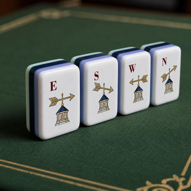May include: Four rectangular mahjong tiles with white faces and layered blue and light blue sides. Each tile features a red letter E, S, W, or N above a graphic illustration of a gold weather vane with an arrow pointing in different directions.