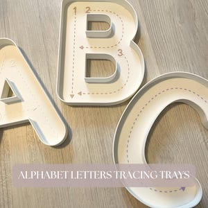 Könnte beinhalten: Drei weiße, buchstabenförmige Schalen in Form von A, B und C. Jede Schale zeigt interne gestrichelte Linien und nummerierte Pfeile, die die Strichreihenfolge zum Schreiben der Buchstaben angeben. Der Text ALPHABET LETTERS TRACING TRAYS ist sichtbar.