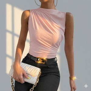 May include: A sleeveless light pink top with a high neckline and gathered fabric detail on the shoulder. The top is paired with black trousers featuring a black belt with a gold-toned buckle and a white quilted clutch bag with a gold chain strap.